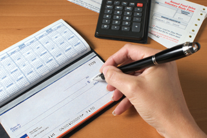 person filling out a check next to a calculator