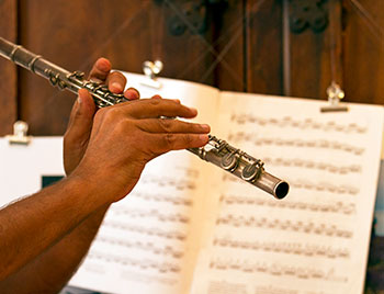 A person playing the flute while reading music