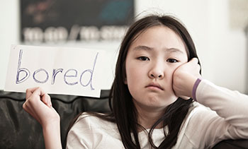 A girl holding up a sign stating she is bored.