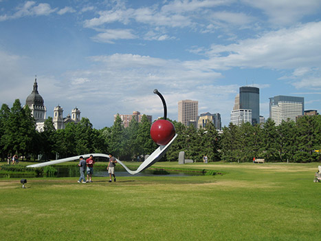 People walking by the sculpture of a giant spoon with a cherry on it in Minneapolis.