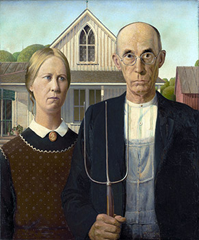 A man and woman farmer posing in front of their home.
